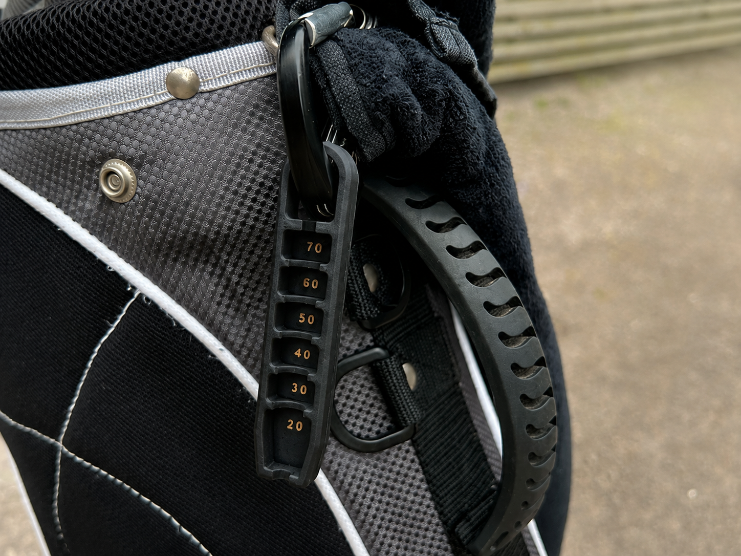 Black Golf Tee Elevator with bronze height markings attached to a golf bag
